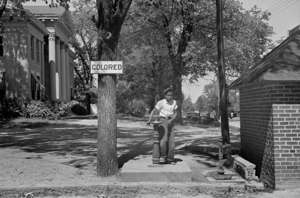 Boy at Drinking Fountain with Sign "Colored" on County Courthouse Lawn, Halifax, North Carolina, USA, John Vachon, Farm Security Administration, April 1938 Trump DEI segregation