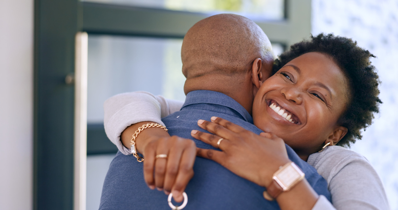 Couple, hug and key in new home or happy for real estate, property investment or celebration by front door. Black people, man and woman with embrace for fresh start, achievement and mortgage or smile