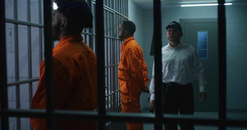 Criminals stand face to cell with hands behind