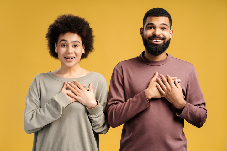 Attractive African American couple, happy man and woman holding hands on heart, gratitude