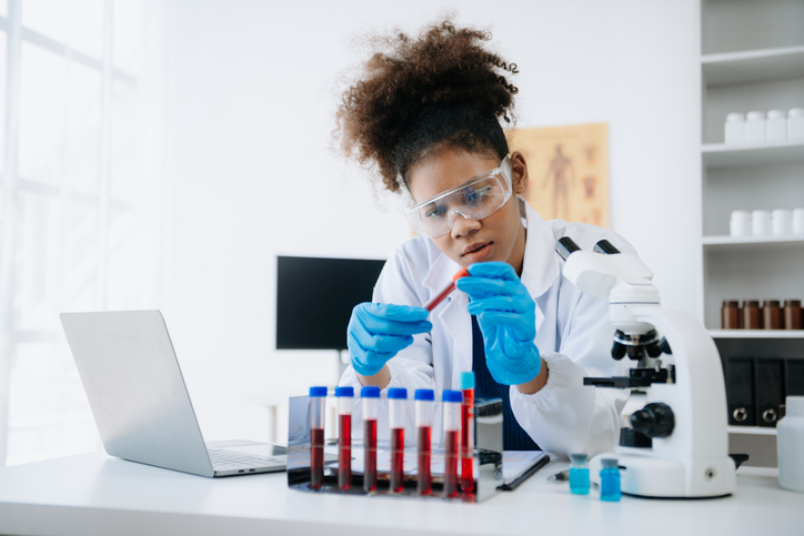 Young scientists conducting research investigations in a medical laboratory, a researcher in the foreground is using a microscope in laboratory for medicine.