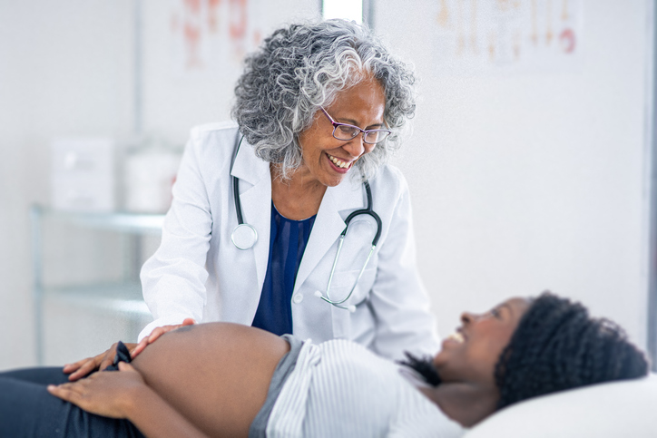 Cheerful obstetrician in appointment with pregnant black woman