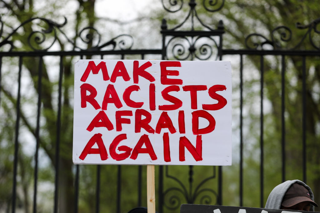 A protester holds up a placard saying "make racists afraid...