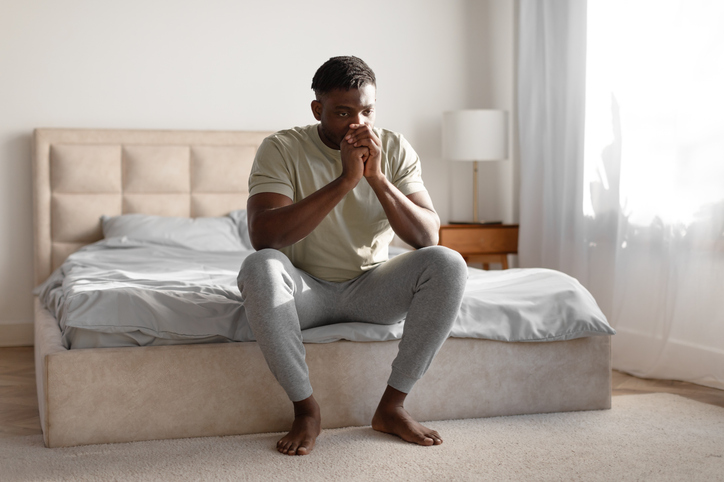 Unhappy Black Young Guy Thinking About Loneliness Sitting On Bed