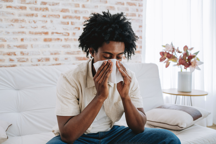 Man sneezing with handkerchief on nose