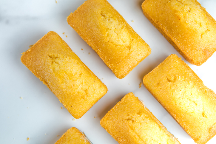 Close-up of corn muffins on plate with bowl of corn meal and additional muffins in the background.