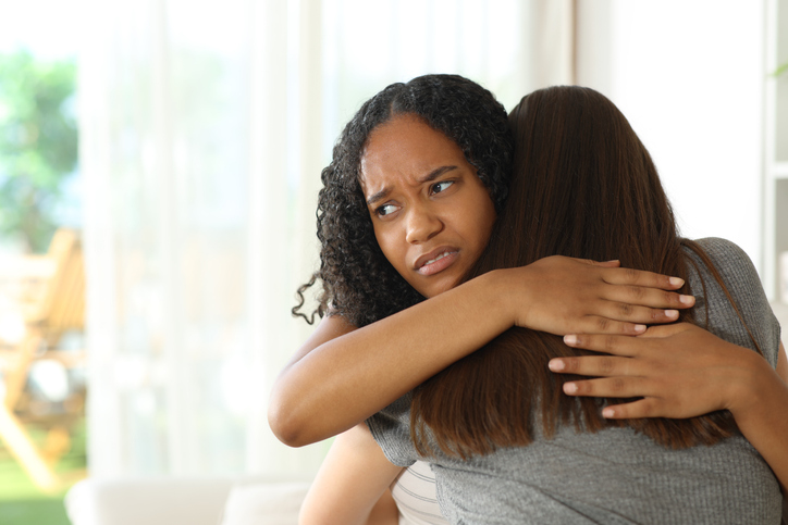 Disappointed false black woman hugging her friend