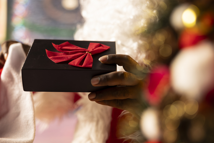 Saint Nicholas wraps a festive gift box surrounded by Christmas lights