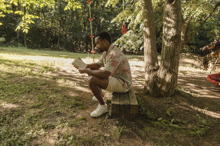 Young man enjoying a book in peaceful garden setting