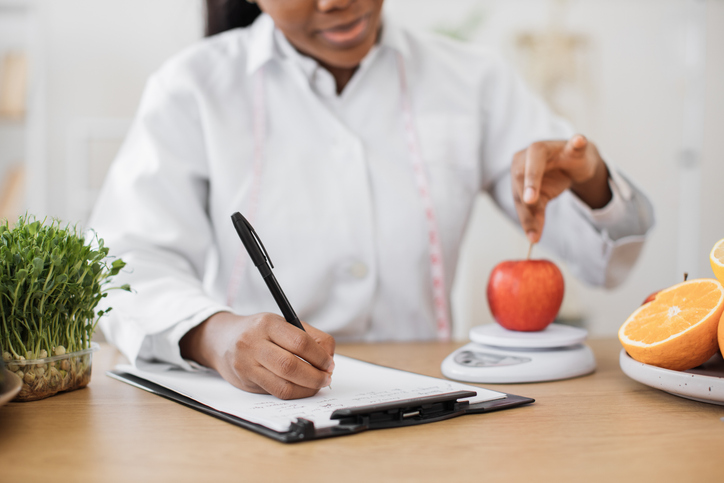 Specialist putting fruit on weighing instrument in office