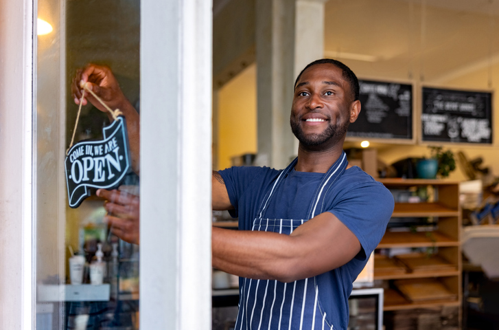 Waiter hanging an open sign on the door at a cafe