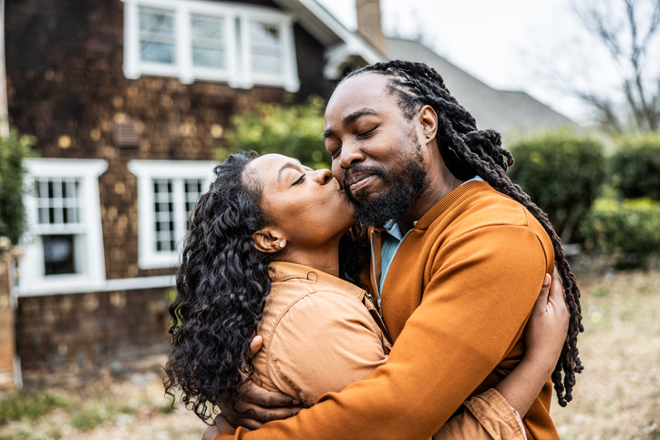 Portrait of young couple in front of their home