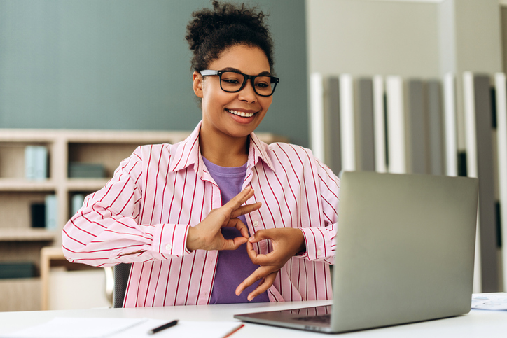 Smiling teacher using sign language during online class