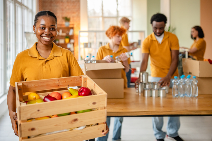 Young volunteers actively support their community through food bank work and charitable activities in a vibrant indoor space
