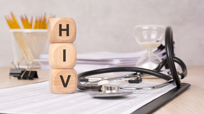 Wooden blocks spelling "HIV" with medical tools, symbolizing awareness, research, and healthcare