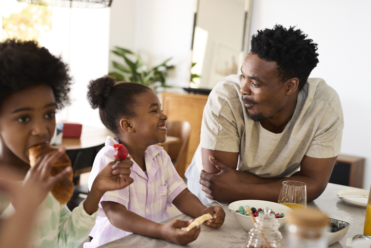 Daughters eating breakfast with father
