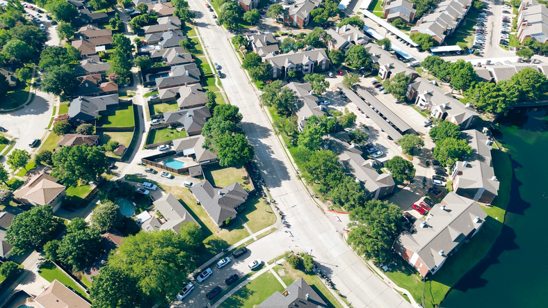 Street parade at lakeside residential neighborhood in Coppell suburbs Dallas, Texas, tree lined residential street, row of single-family houses, swimming pool, fast growing housing market, aerial