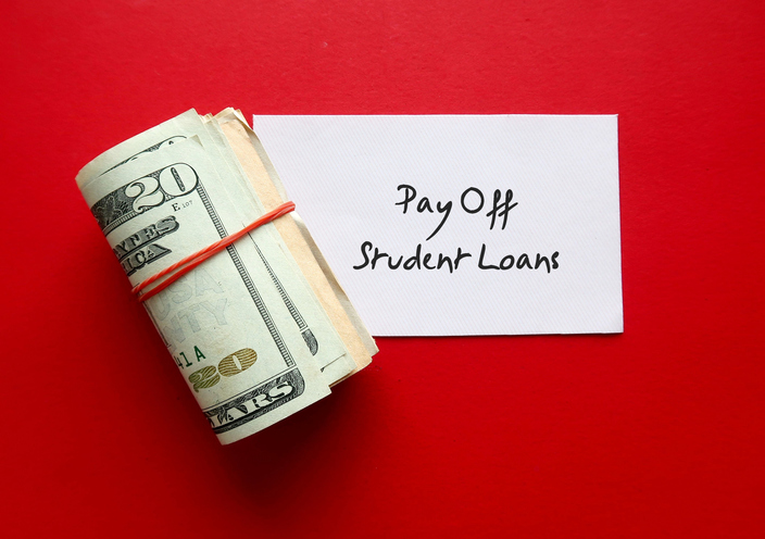 Cash dollars money with note written Pay Off Student Loans - on red background - financial management goal to clear student loan - clarify financial goal, make smart payment strategies, and seek forgiveness resources to clear the debt
