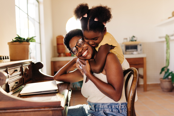 Mother-daughter relationship: Girl holding her mom in a tight hug at home