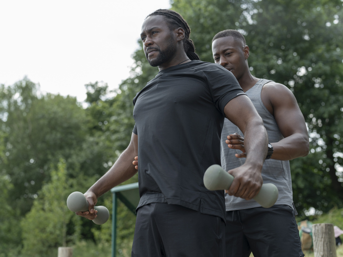 Two men exercising with dumbbells in park