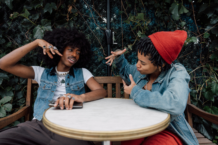 Couple of friends sitting on a sidewalk cafe enjoying a break