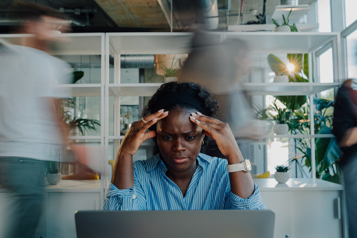 Stressed young african american businesswoman suffering headache in busy office