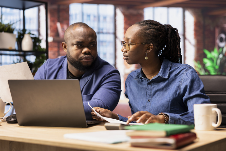 Black man and woman at desk analyzing financial documents and tracking expenses