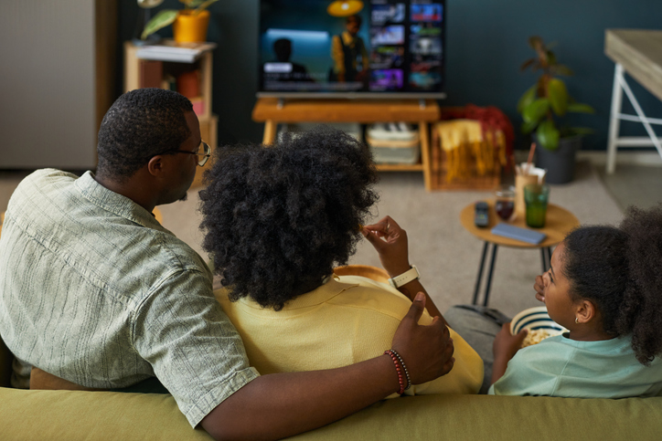 Black Family Relaxing Together Watching Television in Living Room at Home