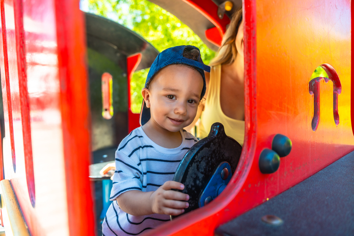 Little boy playing with toy train wheel in playground