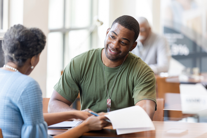 Veterans discuss paperwork, smiling during a professional meeting.